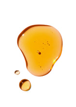 Load image into Gallery viewer, A drop of yellow liquid, presumably the NOURISH healing elixir, on a white background with two smaller drops beside it.
